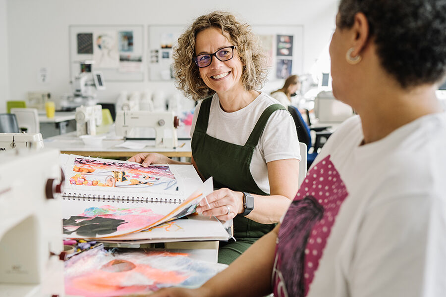 Woman talking to a student over fabric 
