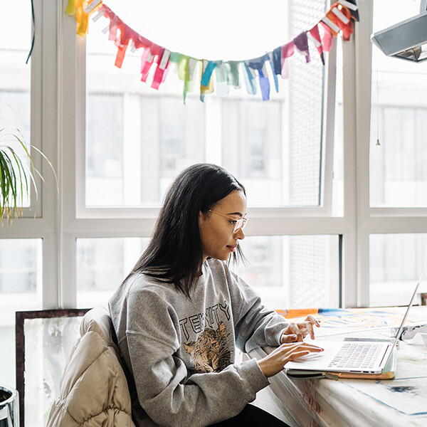 Woman using a laptop in front of a window
