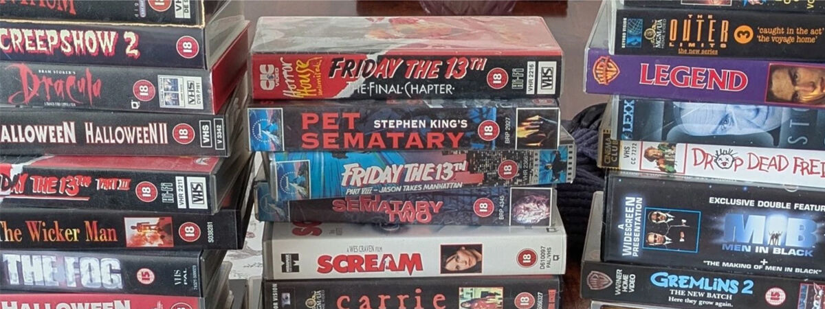 Three stacks of VHS tapes, various vintage horror films