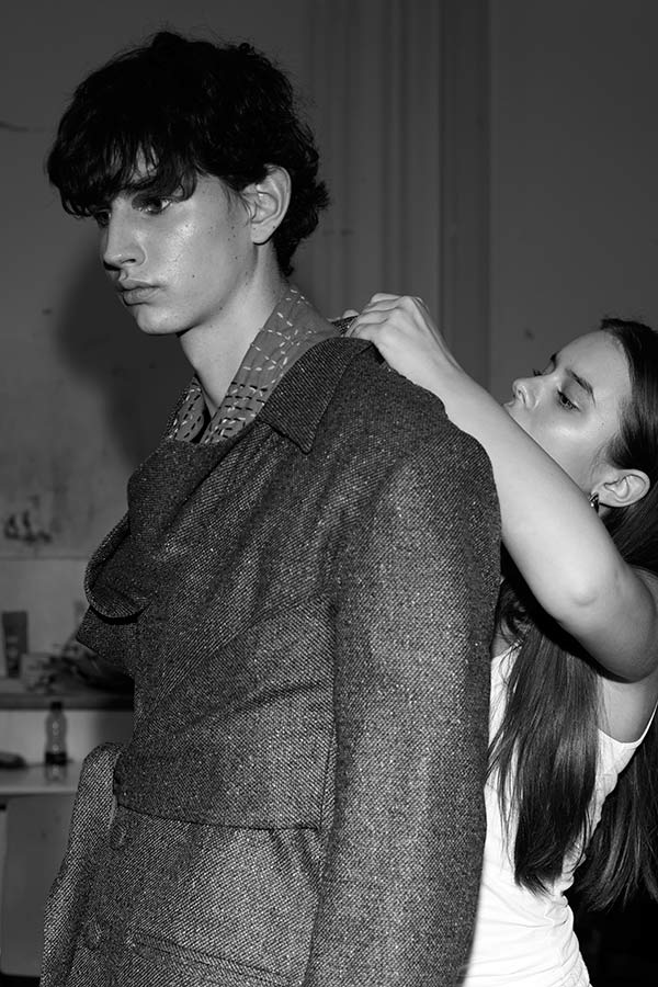 Black and white photo of student working on jacket worn on another student