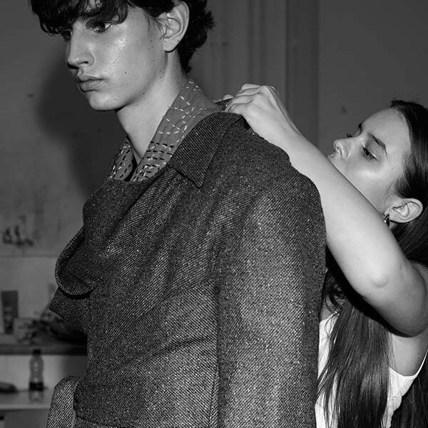 Black and white photo of student working on jacket worn on another student