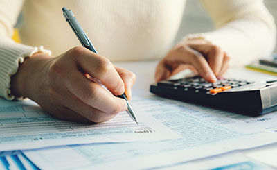 person writing on a piece of paper and using a calculator