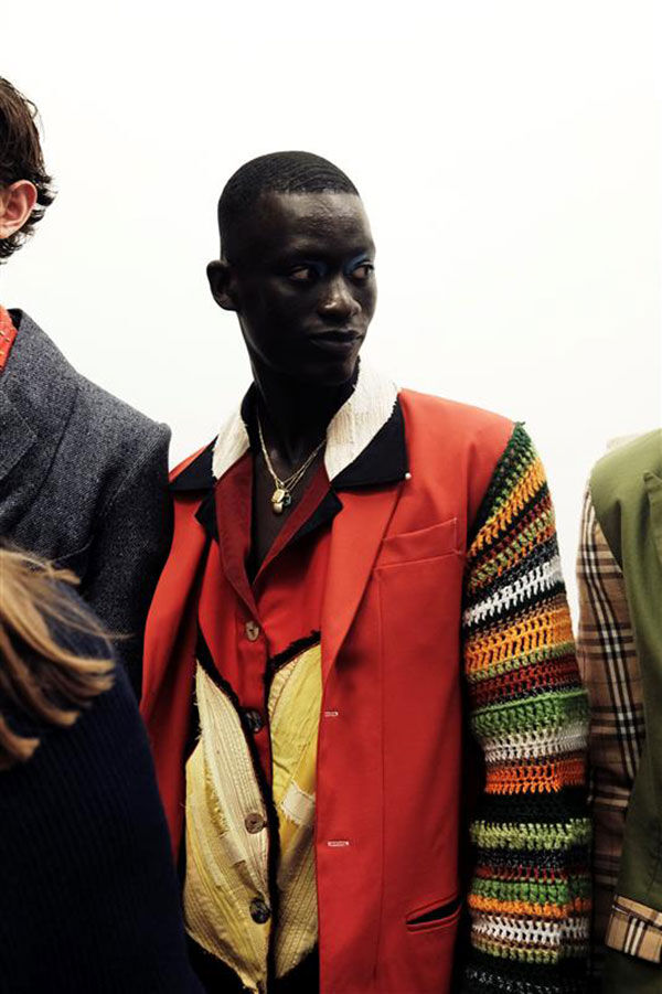 Student in bright coloured shirt and jacket, including orange and yellow shades