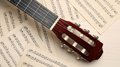 guitar and music notations on light wooden table
