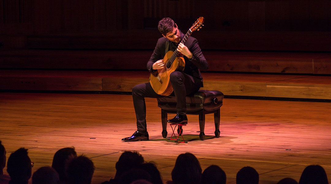 Person performing guitar onstage in front of audience