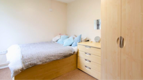 A simple bed and wardrobe in a bedroom