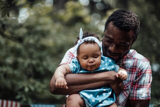 Millennial authentic parent with cute infant spending time together in sun day.