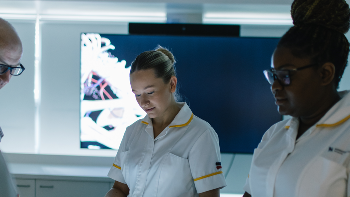 Healthcare students stood observing an anatomage table.