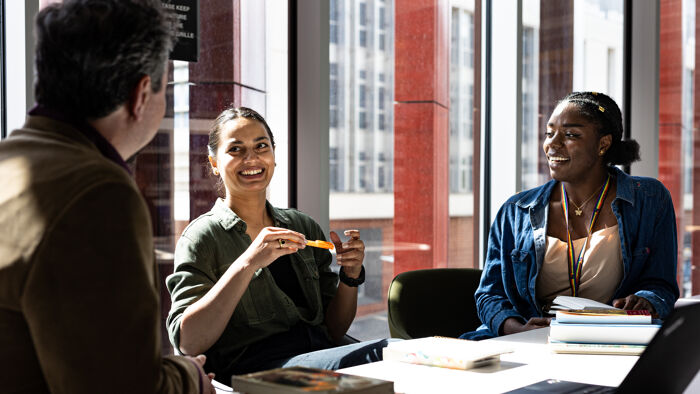 Black woman laughs whilst studying in a red room