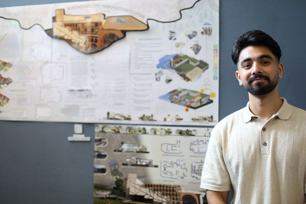 A student stands in front of their project poster for Innovation Festival 2024