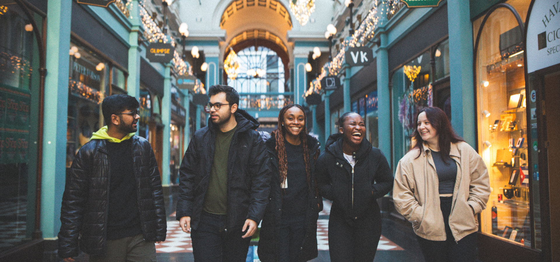 Five students walk through a shopping arcade in Birmingham, 