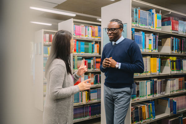 Two students talk in the library