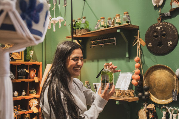 A student shops in Red Brick Market, looking at a small cactus plant in a bottle