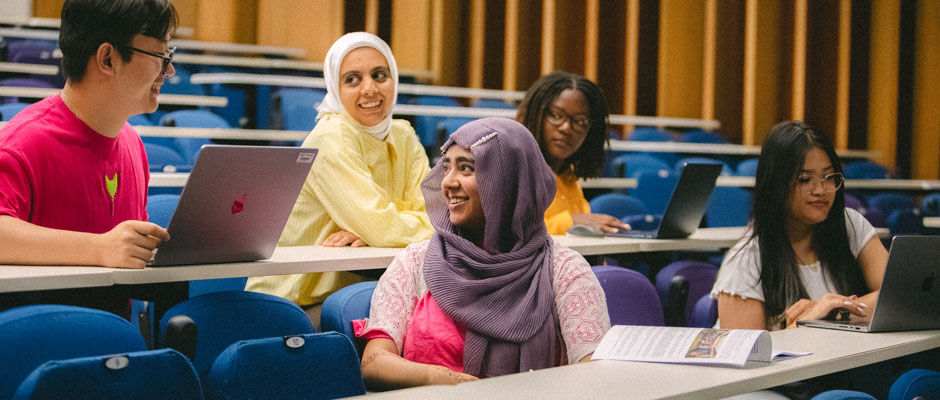 A group of students talking in a lecture theatre