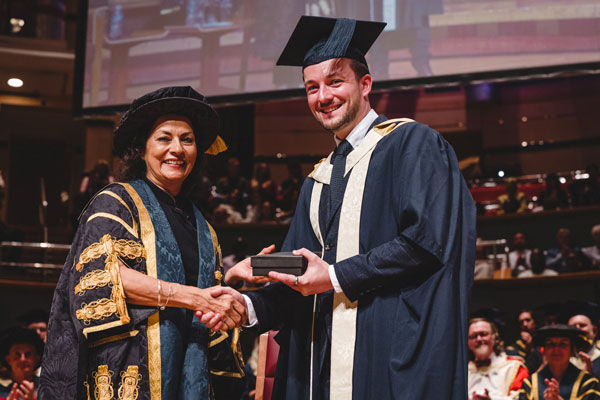 John Burton Alumni of the Year Summer Graduations 2025 shakes hands with Anita Bhalla