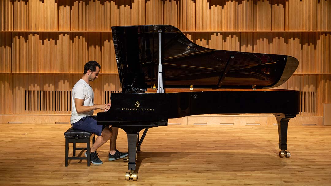 Student playing piano in concert hall