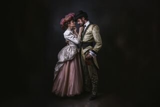 Man and woman in Victorian clothes share tender moment