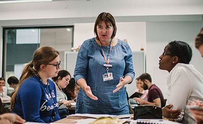 Tutor talking to several students sat around a table.
