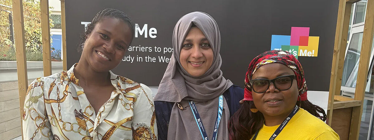 Three postgraduate researchers standing together smiling