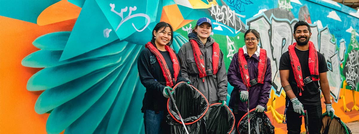 A group of people smiling at the camera with litter picking equipment