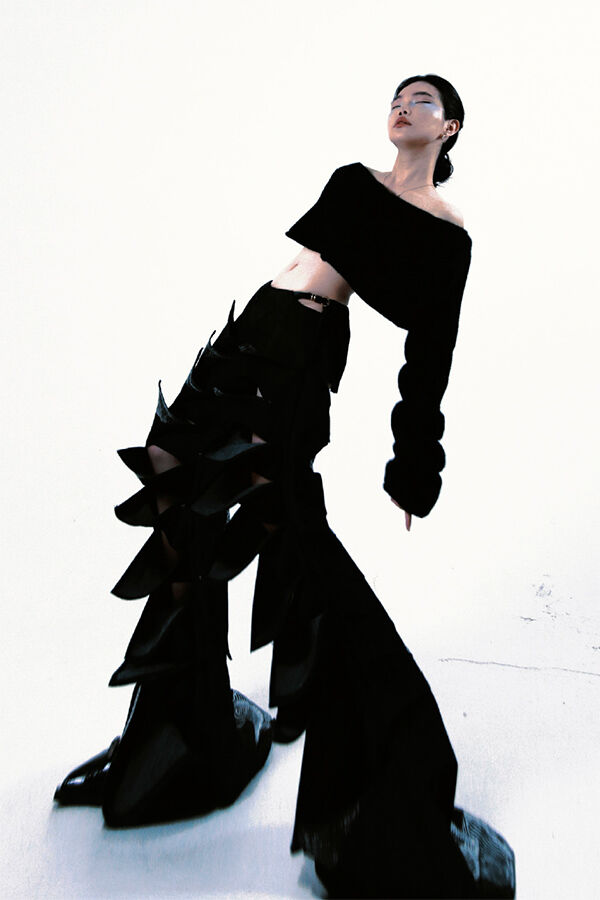 Model in spikey black trousers and top