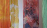 Fabric pieces with watercolour-like patterns hang vertically, featuring yellow, orange, red, blue, and green hues.