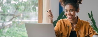 A young person looking at their laptop smiling