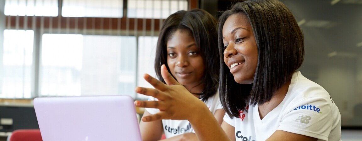 Two students looking at a laptop and talking