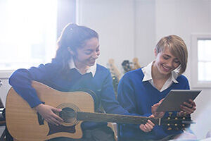 Kids playing guitar and composing on tablet