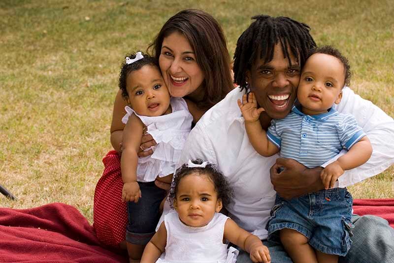 Two adults and three babies sitting on the grass 