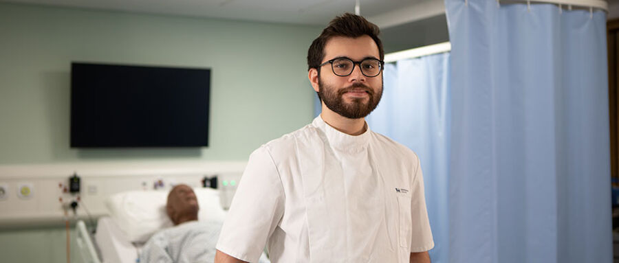 Nicholas stands in front of a hospital bed in one of our mock hospital wards