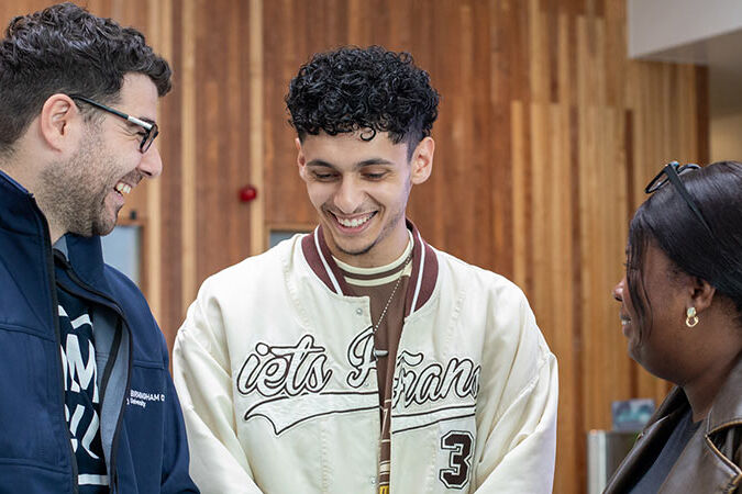 A member of BCU staff helping two visitors at an open day