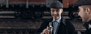 Peaky Blinders Response 1200x450 - Two men in peaky caps with alcohol
