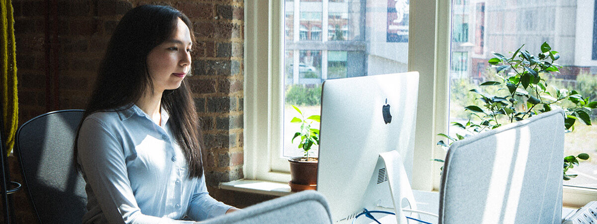 Postgraduate student sat at Mac computer