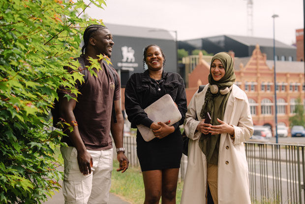 three postgraduate students walking through campus