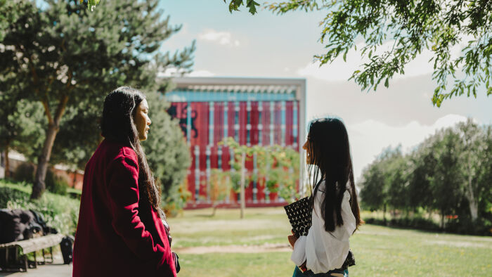 Two students stand in front of the red curzon building