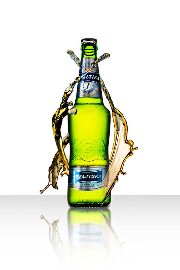 Photography piece of green beer bottle with beer surrounding the bottle