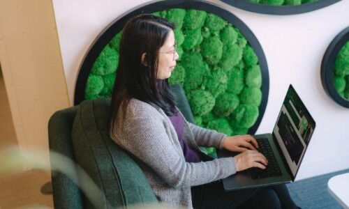 Person sat at desk with laptop and reading a letter