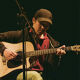 Member of the Quench Arts community group playing guitar on stage