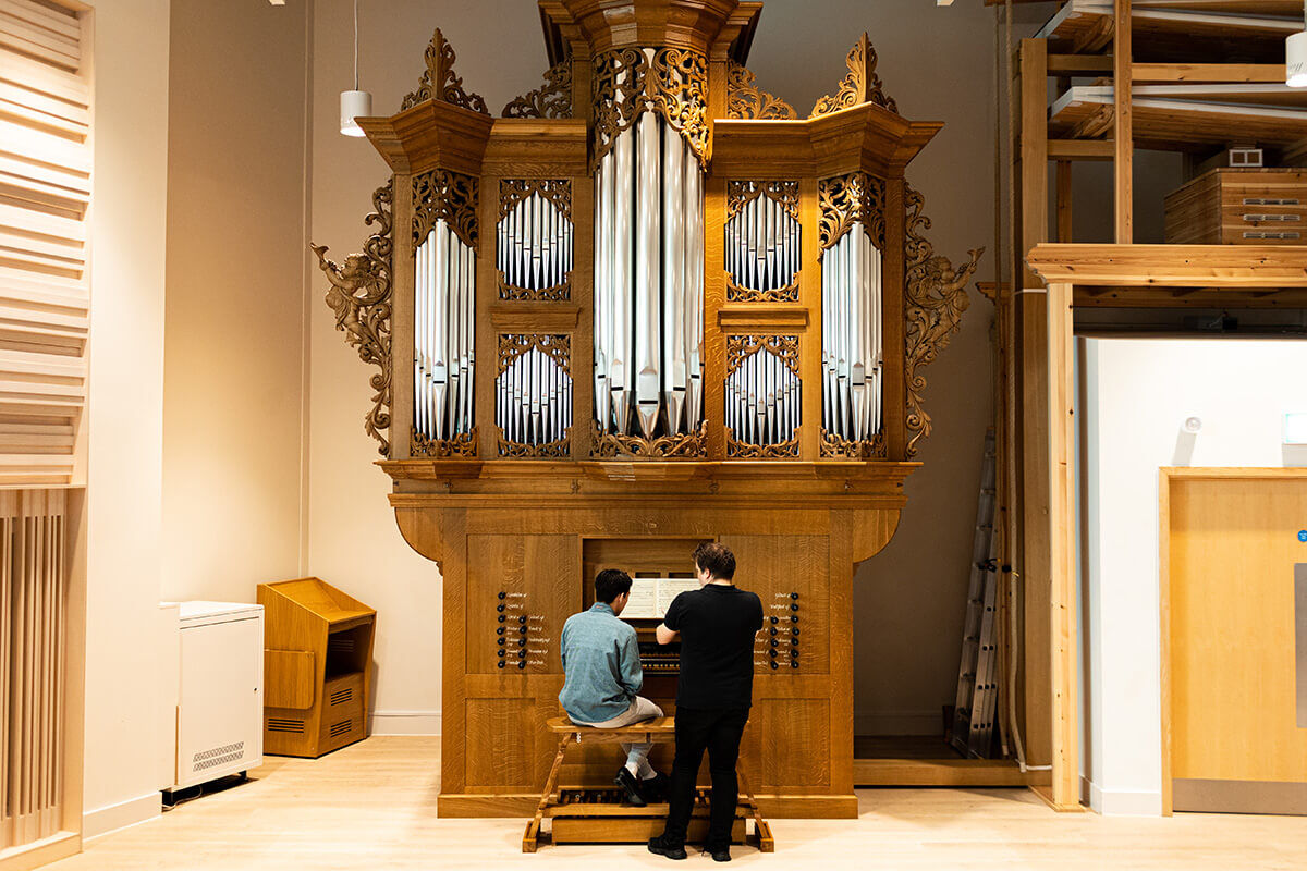 Student playing organ with tutor looking on