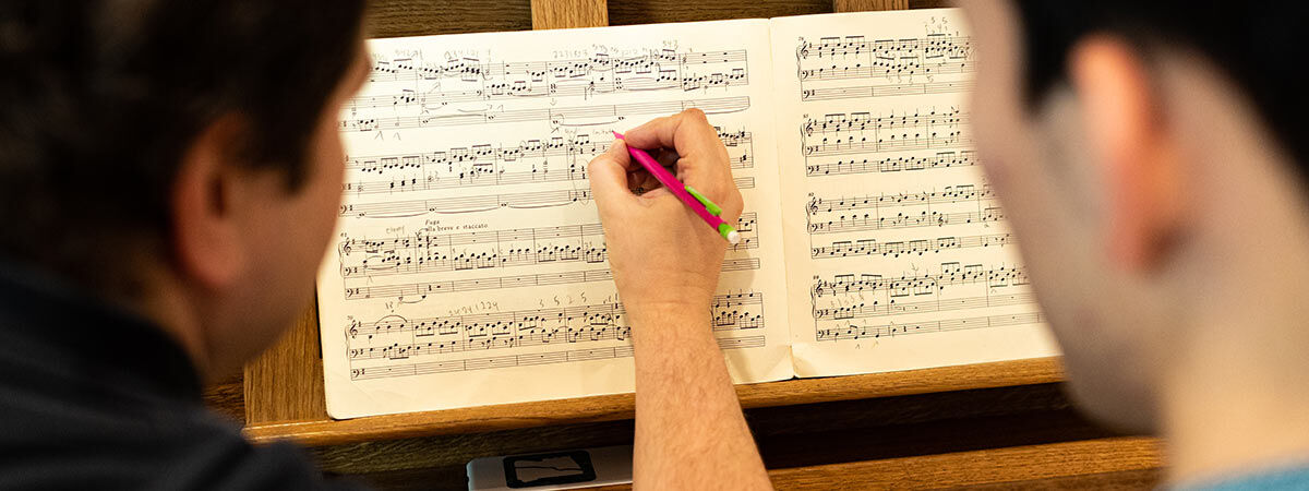 A person is helping someone by writing on music sheets 