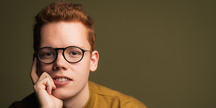 Young man posing with hand resting on chin looking towards the camera 