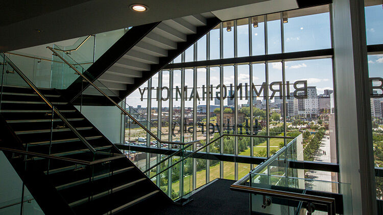 Interior of Curzon building showing BCU logo through window on stairs