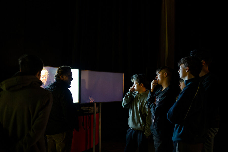 Students looking at screen, stood with lecturer