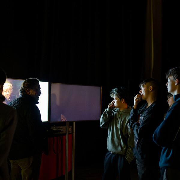 Students looking at screen, stood with lecturer