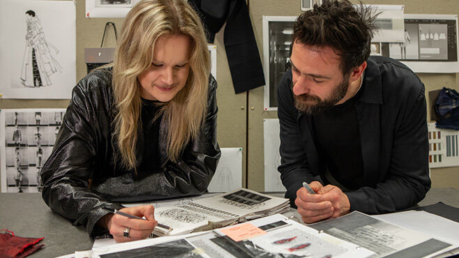 Fashion student and lecturer at table whilst student is drawing in sketchbook