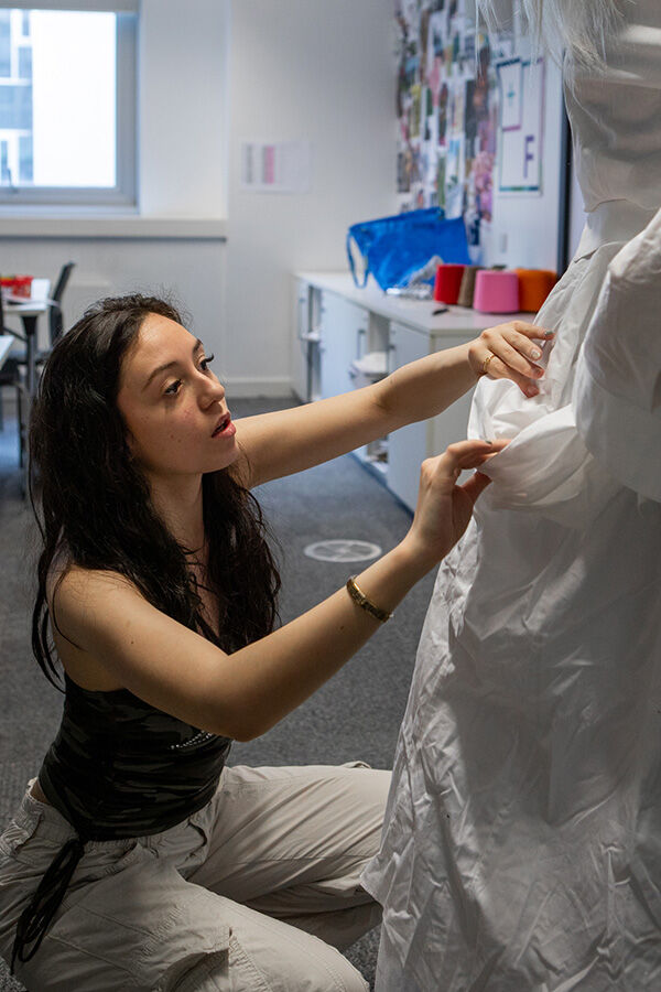 Student dressing a mannequin with wedding style gown