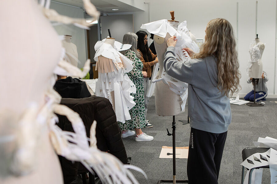 Student styling white garment on mannequin in workshop