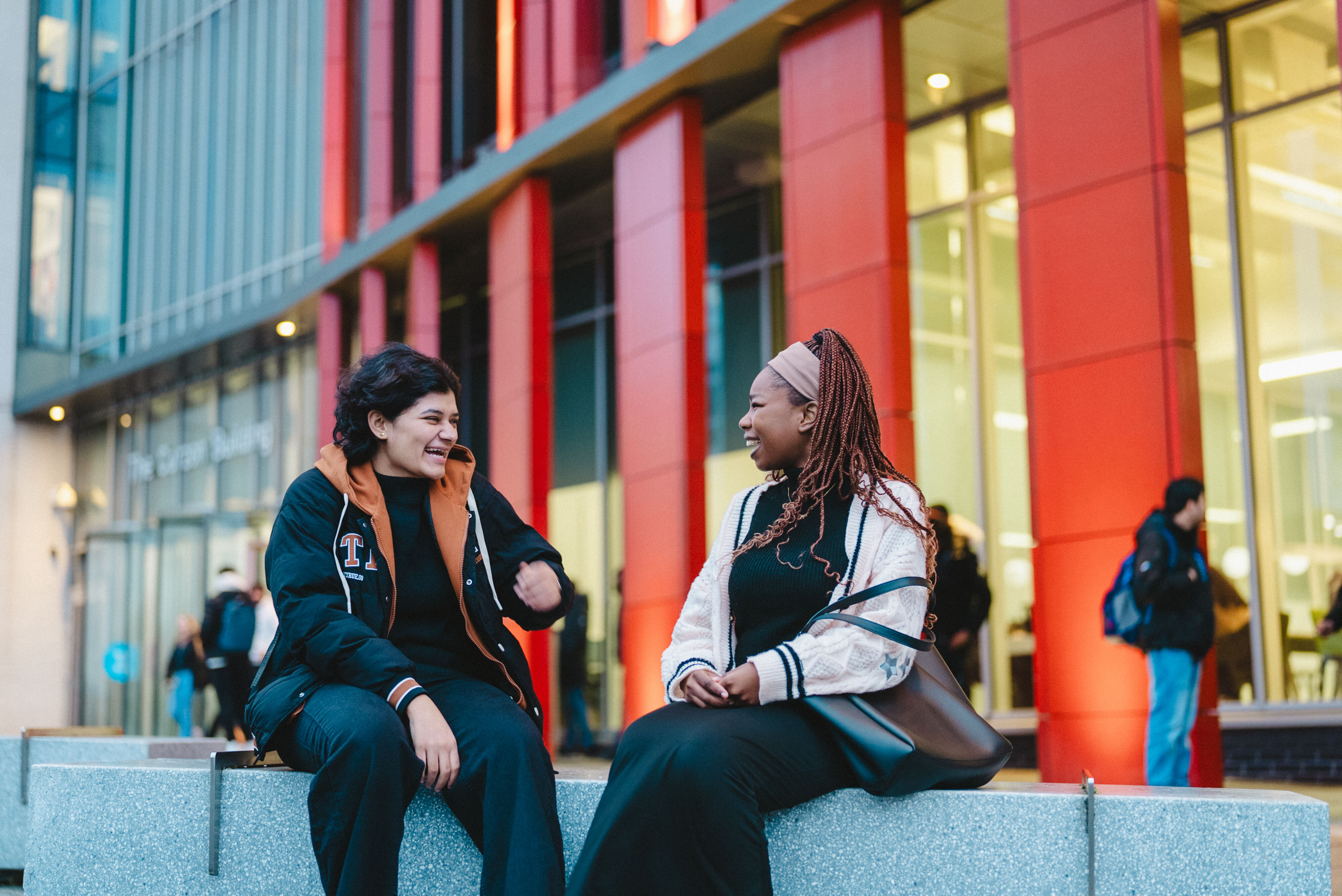 Two International Students Chatting Outside Red Curzon Building