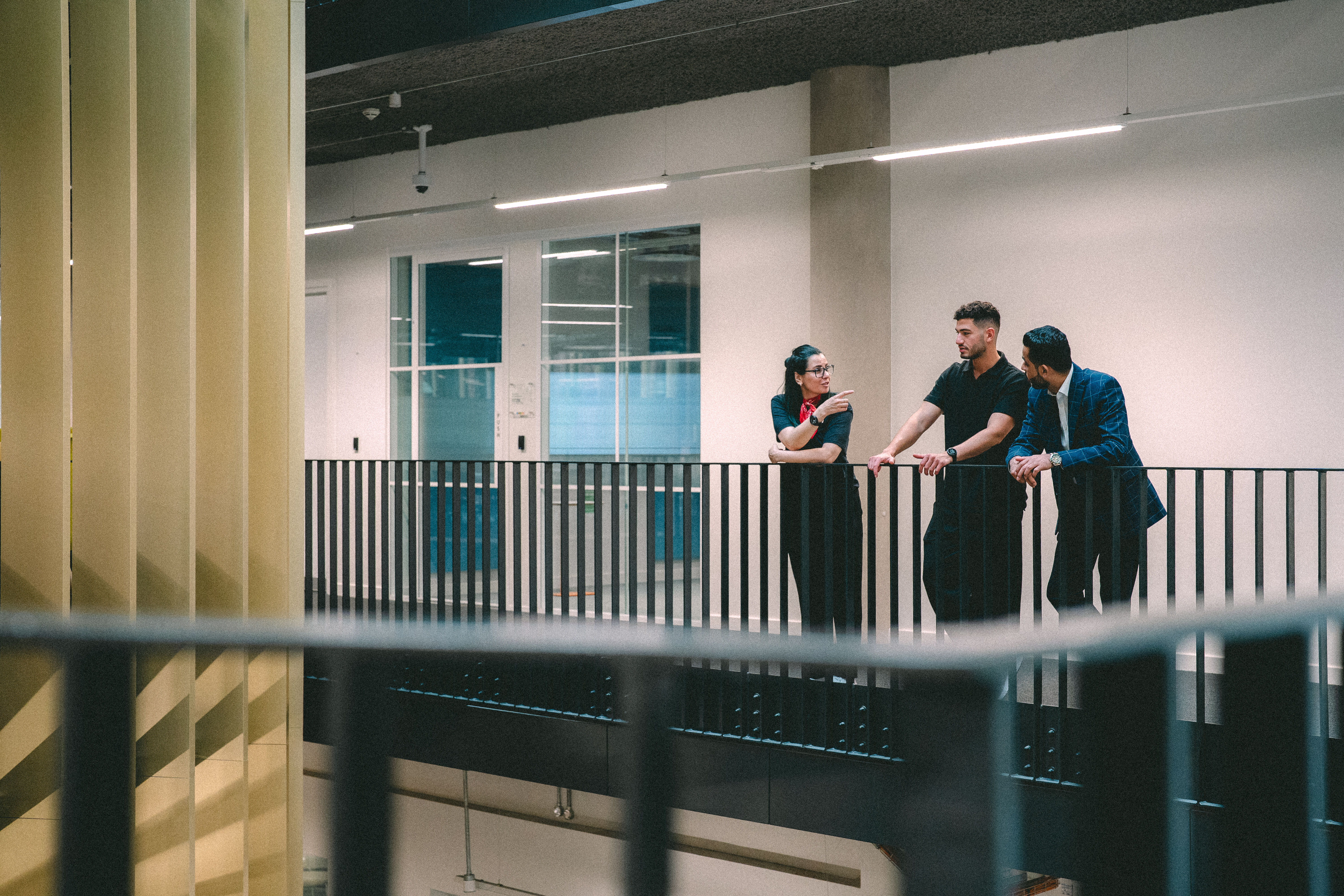 Three students stood on a balcony chatting